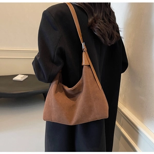 Détail du sac sous le bras en daim marron avec bandoulière en cuir et boucle argentée
