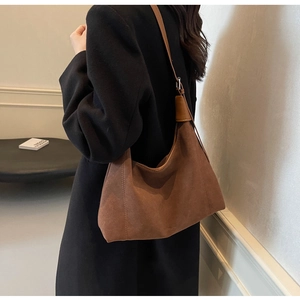 Sac hobo en daim marron vue latérale avec coutures décoratives et bandoulière réglable