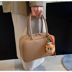 Detailed texture of caramel lychee grain leather on a mini Boston bag with plush bear