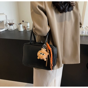 Detail view of black lychee-grain bowling bag with cute plush pendant on a model