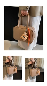 Detail der beige Handtasche aus Leder mit Plüschanhänger und orangefarbenem Seil