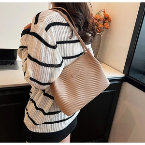 Detail of khaki pleated bucket tote bag showing vertical ripple texture and fashion tag