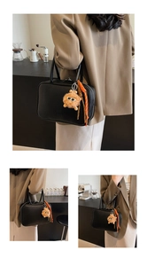 Detail der schwarzen Bowlingtasche aus Leder mit orangefarbenem Monster-Anhänger und Reißverschluss