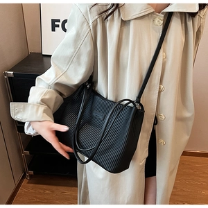 Detail of black pleated bucket bag showing vertical texture and rectangle logo patch
