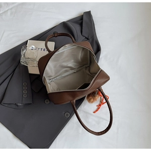 Detail of a dark brown pebble leather bowling bag showing its spacious zipper opening