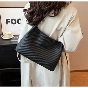 Detail of black pleated shoulder bag with embossed logo and textured surface