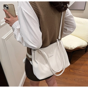 Detail of white corduroy tote bag showing textured fabric and versatile strap design
