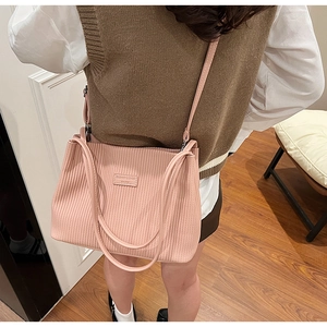 Close-up of pink corduroy tote bag featuring fine stripes and decorative logo patch