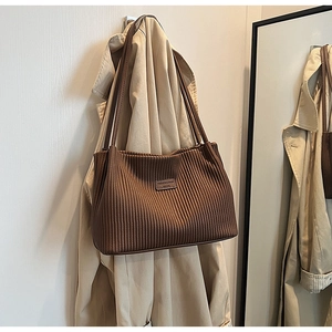 Detail of dark brown pleated tote bag featuring a metallic fashion logo label