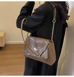 Detail of dark brown vintage shoulder bag with gold chain strap and textured leather finish