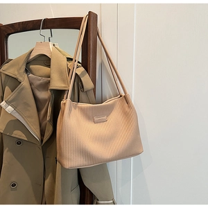 Detailed texture of beige corduroy bucket bag with rectangular leather patch and slim straps