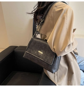 Detail of vintage gray crossbody bag featuring a golden metal buckle and chain strap