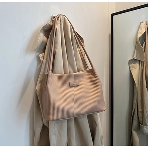 Detail of beige pleated hobo bag showing vertical texture and Fashion & Bags tag on coat