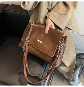 Detail of vintage brown crossbody bag with gold buckle on a beige trench coat