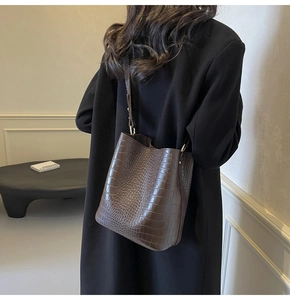 Close-up of dark brown crocodile embossed texture on luxury bucket bag with shiny finish
