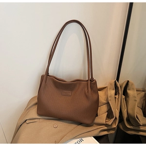 Detail of a brown pleated bucket bag with long shoulder straps on a stylish blazer