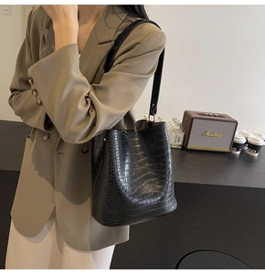 Side view of black crocodile pattern bucket bag on model for professional daily commute