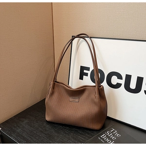 Detail shot of brown pleated texture and leather logo patch on large bucket bag