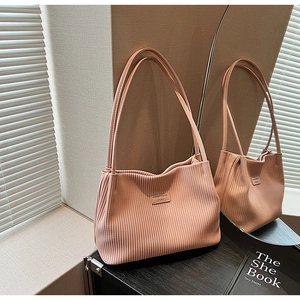 Detail shot of the vertical pleated texture and dual straps on this peach bucket bag