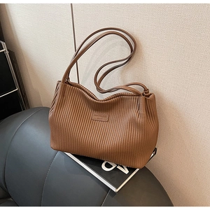 Close-up of brown pleated texture leather and brand logo on minimalist bucket bag