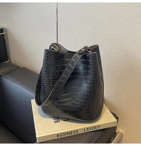 Detail of black crocodile pattern bucket bag on book featuring silver metal buckle