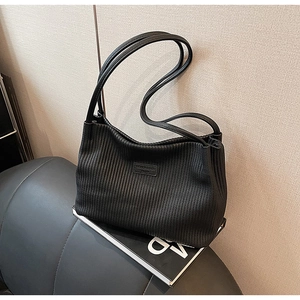 Detail of black pleated bucket bag featuring narrow leather straps and fashion label
