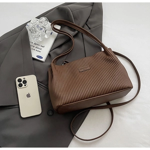Macro view of dark brown pleated texture and leather brand patch on tote bag