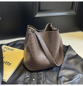 Detailed close-up of brown crocodile texture on a leather bucket bag for daily commute