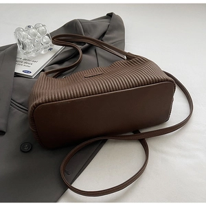 Detailed close-up of dark brown pleated texture and leather finish on a bucket bag
