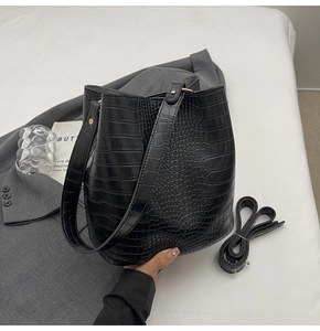 Detail of black crocodile embossed bucket bag with adjustable straps and gold hardware