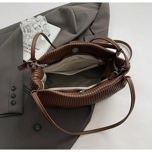 Detail of brown pleated bucket bag interior with magnetic clasp and zipper pocket