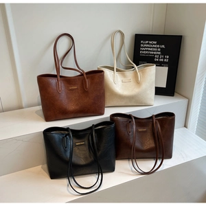 Close-up of four large minimalist tote bags in black, beige, and brown with lychee texture