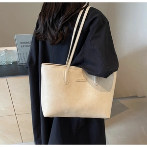 Detail showing beige large capacity tote bag with textured leather and fashion plaque