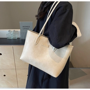 Detail of a large cream tote bag with crinkled faux leather texture on model's shoulder