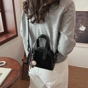 Detail of a matte black crossbody bag with a baseball charm and Yaziandi logo