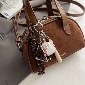 Detail of vintage matte brown leather handbag featuring a unique baseball charm accessory