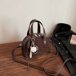 Detail of dark brown matte leather crossbody bag with creative sports charms on wood