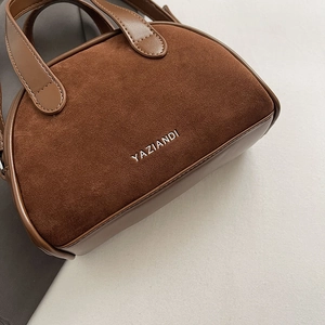 Detail of dark brown vintage matte crossbody bag with polished leather and suede stitching