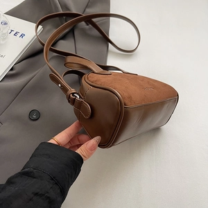 Detail of a brown cylindrical crossbody bag featuring a vintage leather and suede patchwork