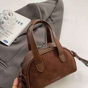 Close-up of vintage brown suede and leather stitching handbag with YAZIANDI logo