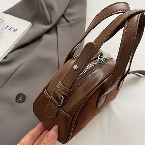 Detail showing the brown leather patchwork top with silver zipper and double handles