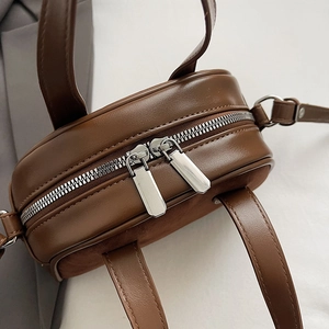 Detail view of smooth brown PU leather bag with premium dual silver metal zippers