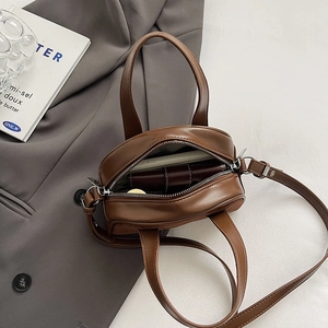 Detail view of mini vintage matte brown crossbody bag with double handles and open zipper