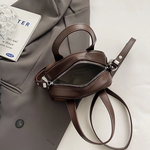 Detail view of mini dark brown crossbody bag with open zipper and interior lining