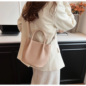 Detailed view of apricot pleated bucket bag with round handles and crossbody strap