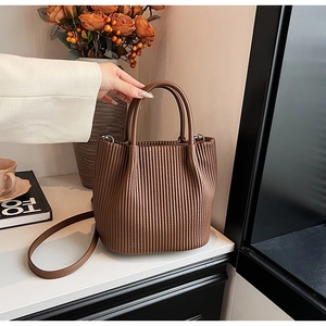 Close-up of brown pleated bucket bag showing leather texture and soft handle details