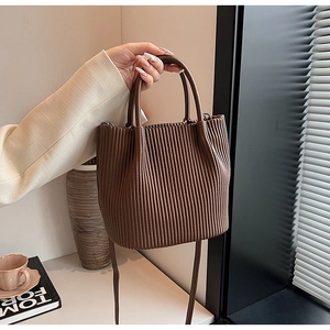 Detail of deep brown pleated texture bucket bag with dual handles and smooth leather finish