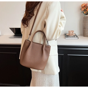 Detail shot of brown pleated PU leather bucket bag featuring a vertical textured finish