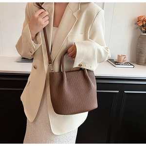 Detail of dark brown pleated bucket bag showing vertical texture and silver hardware