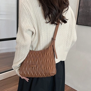 Brown pleated shoulder bag with adjustable strap worn by model in casual setting